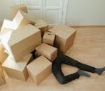 A person overwhelmed by cardboard boxes during a home move, symbolizing stress and relocation.